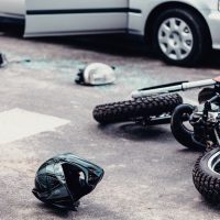 Helmet and motorcycle next to broken peaces of a car on the street after car crash
