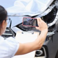 Agente de seguros toma fotos de los daños al auto después de un accidente