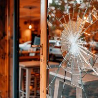 Daños a propiedad: Cristal destrozado en el escaparate de una cafetería moderna