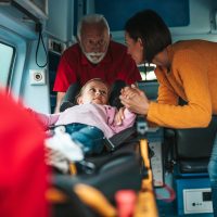 Scared mother standing with doctors and her injured daughter.