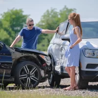 a-man-and-woman-stand-near-the-damaged-front-of-a-black-car-and-the-dented-side-of-a-white-suv[1]