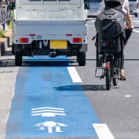 a-cyclist-rides-in-a-designated-blue-bike-lane-beside-a-white-truck-on-a-sunny-urban-street[1]
