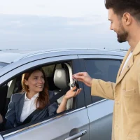 a-woman-in-a-car-smiles-as-she-receives-keys-from-a-man-outside[1]